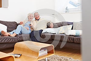 Senior Couple Sitting On Sofa Watching TV