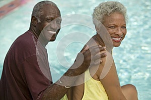 Senior Couple sitting by swimming pool portrait.