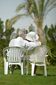 Senior couple sitting at tropic hotel garden