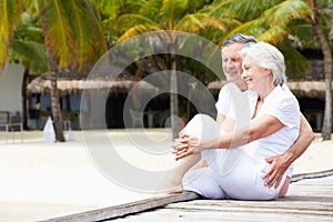 Senior Couple Sitting On Wooden Jetty