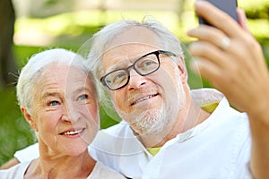 Senior couple with smartphone taking selfie in summer
