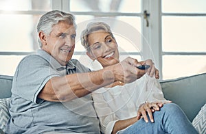 Senior couple, smile and hug watching TV for entertainment on living room sofa with remote at home. Happy elderly man