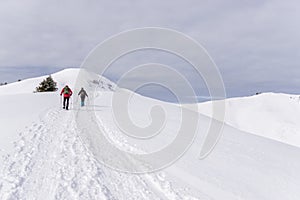 Senior couple is snowshoe hiking in alpine snow winter mountains. Allgau, Bavaria, Germany.