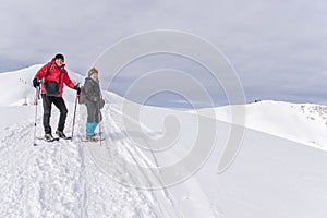 Senior couple is snowshoe hiking in alpine snow winter mountains. Allgau, Bavaria, Germany.