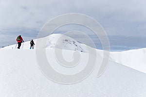 Senior couple is snowshoe hiking in alpine snow winter mountains. Allgau, Bavaria, Germany.