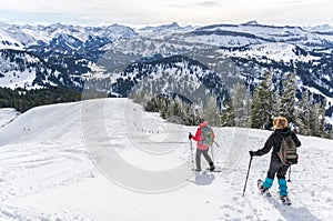 Senior couple is snowshoe hiking in alpine snow winter mountains. Allgau, Bavaria, Germany.