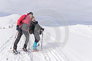 Senior couple is snowshoe hiking in alpine snow winter mountains. Allgau, Bavaria, Germany. photo