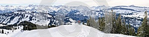 Senior couple is snowshoe hiking in alpine snow winter mountains panorama. Allgau, Bavaria, Germany.