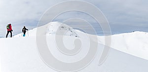 Senior couple is snowshoe hiking in alpine snow winter mountains panorama. Allgau, Bavaria, Germany.