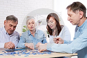 Senior couple solving jigsaw puzzle together with family at home