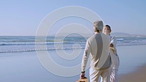 Senior couple spinning around holding hands at seashore