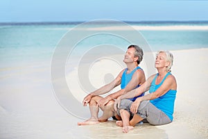 Senior Couple In Sports Clothing Relaxing On Beautiful Beach