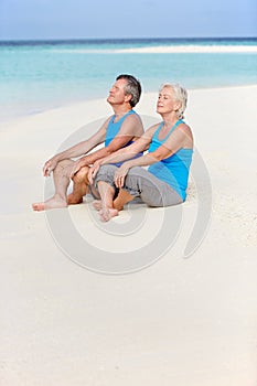 Senior Couple In Sports Clothing Relaxing On Beautiful Beach