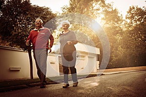 Senior couple in sports clothing running together on roa