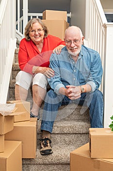 Senior Couple On Stairs Surrounded By Moving Boxes