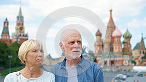 Senior couple stand on Basil`s Descent looking around city. Pensioners traveling in Moscow, Russia