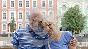Senior couple stand on quay of canal look at camera. Pensioners travel in Saint Petersburg, Russia