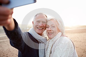 Senior Couple Standing On Beach Taking Selfie