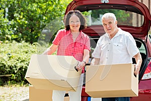 Senior Couple Standing In Front Of Car