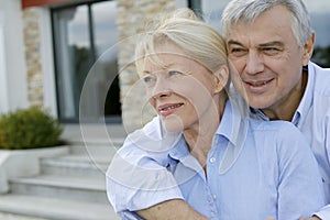 Senior couple standing on front of their new home