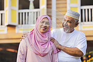 Senior couple standing in front of wooden house