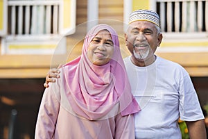 Senior couple standing in front of wooden house