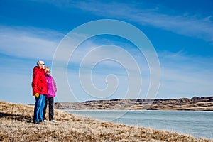 Senior couple standing overlooking an ice-covered Lake Diefenbaker