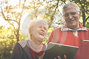 Senior couple standing in park and using iPod.