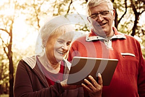 Senior couple standing in park and using iPod. Close up