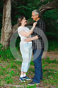 Active loving senior couple walking in beautiful summer forest