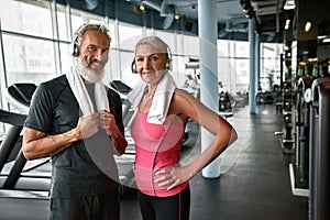 Senior couple with strong bodies and good spirits posing in gym