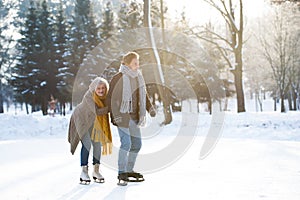 Senior couple in sunny winter nature ice skating.