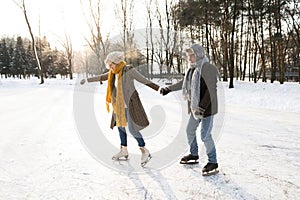 Senior couple in sunny winter nature ice skating.