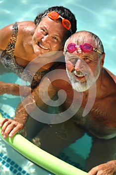 Felice coppia di pensionati divertirsi in piscina luminoso in corrispondenza di occhiali.
