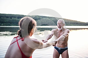 Senior couple in swimsuit standing in lake outdoors before swimming.