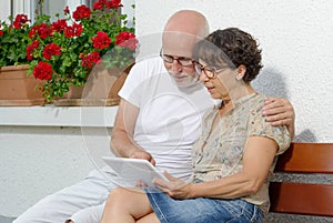 Senior couple with a tablet, outside