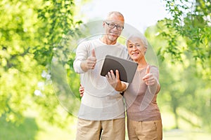 Senior couple with tablet pc showing thumbs up