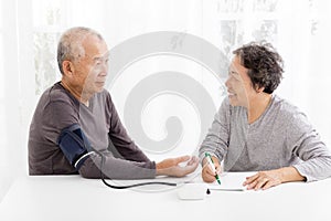 Senior couple taking blood pressure in living room