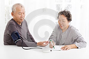 Senior couple taking blood pressure in living room