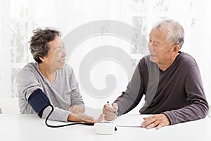 Senior couple taking blood pressure in living room