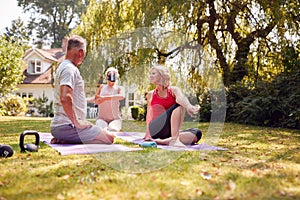 Senior Couple Taking Part In Private Socially Distanced Yoga Class With Teacher At Home