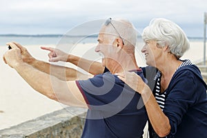 senior couple taking picture sea
