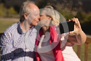 Senior couple taking selfie with mobile phone while kissing each other