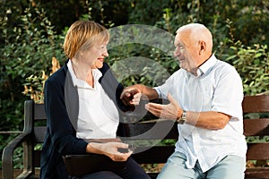 Senior couple talking on bench in park