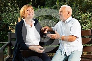 Senior couple talking on bench in park