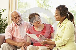 Senior Couple Talking To Financial Advisor At Home