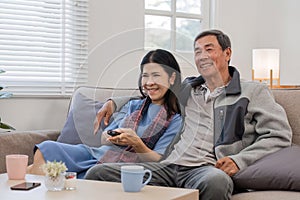 A senior couple in their 60s spends their free time relaxing and having fun together on the sofa in the living room.