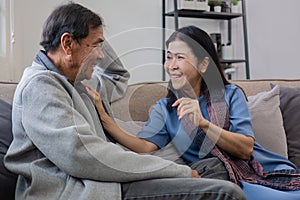 A senior couple in their 60s spends their free time relaxing and having fun together on the sofa in the living room.