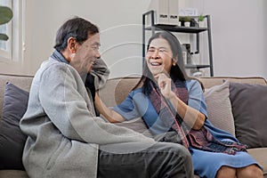 A senior couple in their 60s spends their free time relaxing and having fun together on the sofa in the living room.