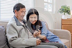 A senior couple in their 60s spends their free time relaxing and having fun together on the sofa in the living room.